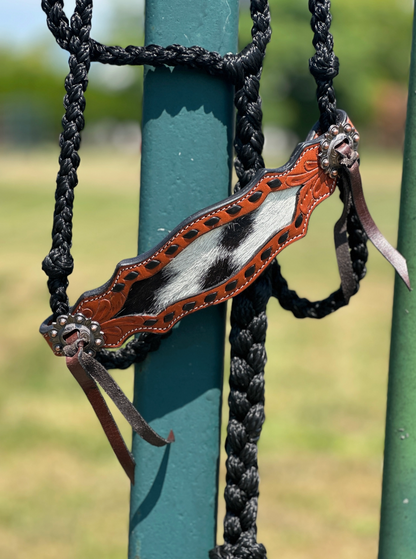 Leather and metal equestrian bridle hanging on a green post with a blurred natural background