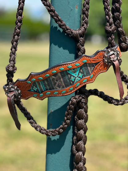 Decorative horse bridle with intricate designs hanging on a blue post outdoors.