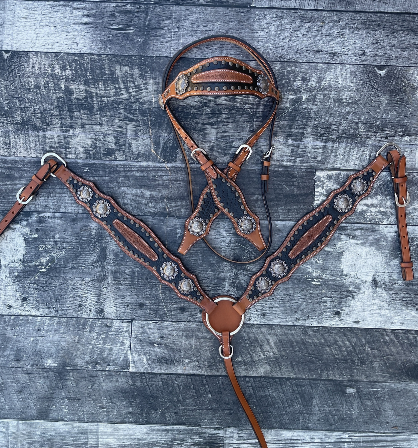 Brown leather horse bridle with decorative studs on a wooden surface