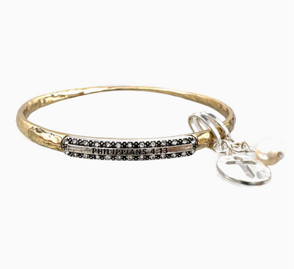Gold bracelet with black beaded bar and cross charm on a white background