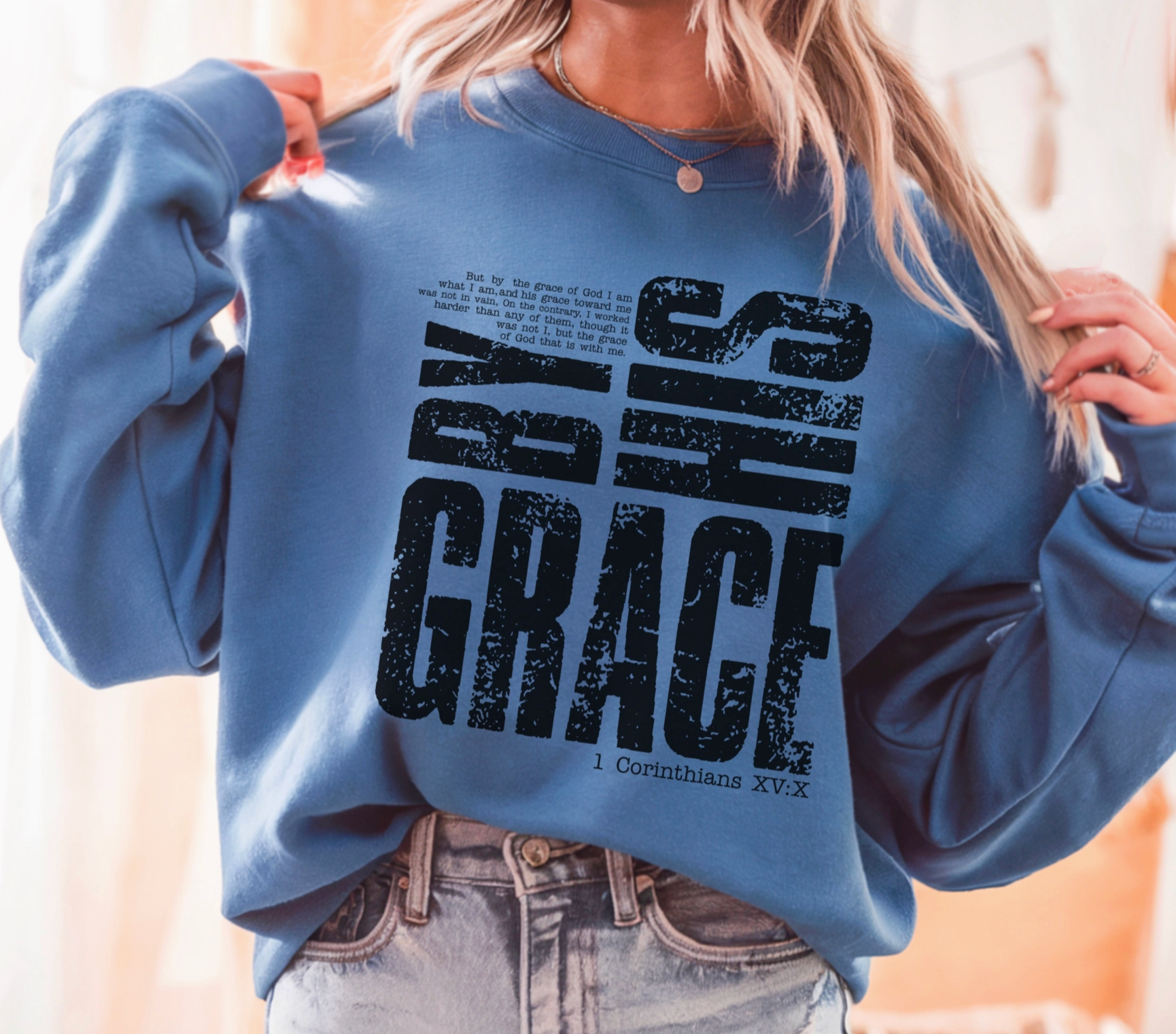 Person wearing a blue sweatshirt with 'GRACE' printed on it, blurred background