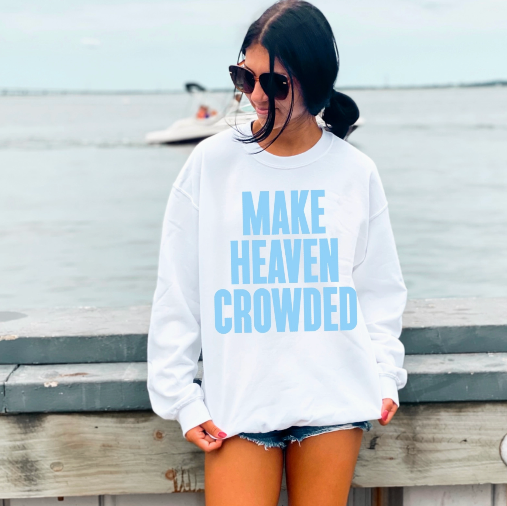 Person wearing a white sweatshirt with blue text sitting on a wooden bench.