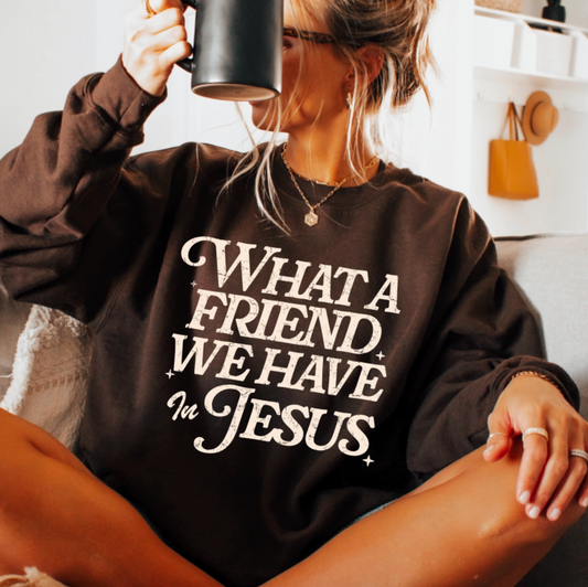 Person wearing a brown sweatshirt with text, holding a mug indoors.
