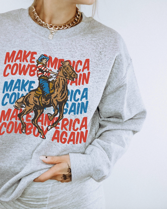 Gray sweatshirt with a graphic of a cowboy on a horse and text 'Make Cowboy America Again' on a white background.