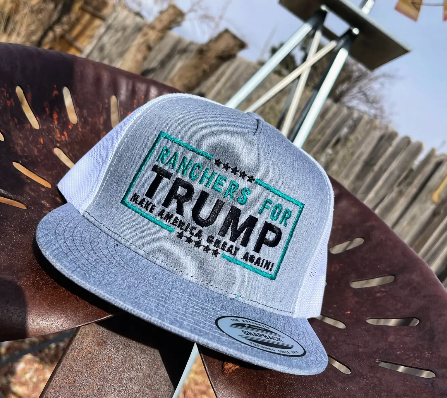 Gray cap with 'Ranchers for Trump' text on a wooden surface
